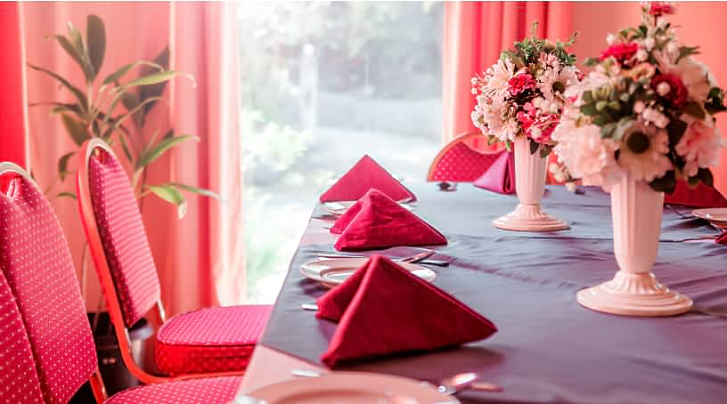 A bright pink dining room, with fuchsia napkins set among floral centerpieces.