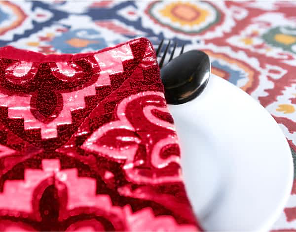 Un couvert sur une nappe éclatante avec une serviette fuchsia aux imprimés vifs.