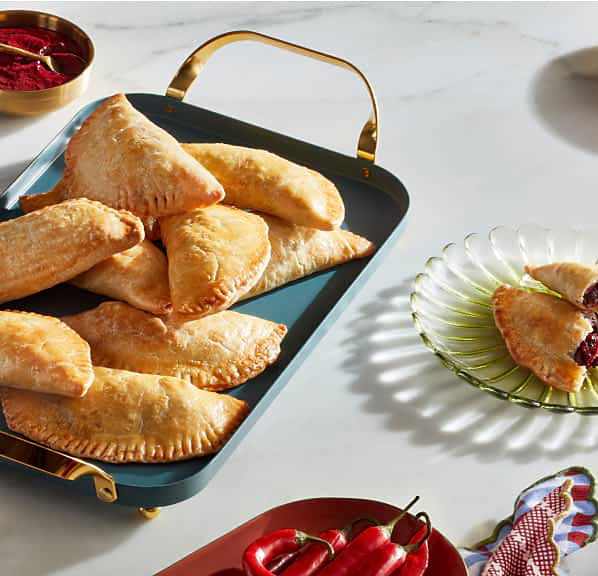 Hibiscus flavored empanadas served on a tray with different dishes on the countertop.