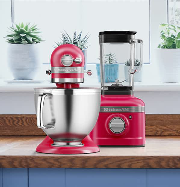 An Artisan® Series Stand Mixer and K400 Variable Speed Blender in Hibiscus on a countertop with different plants in the background.