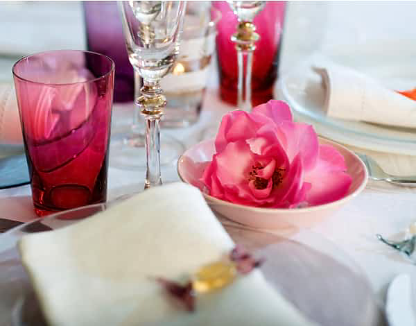 A place setting on a table with pink floral accents.