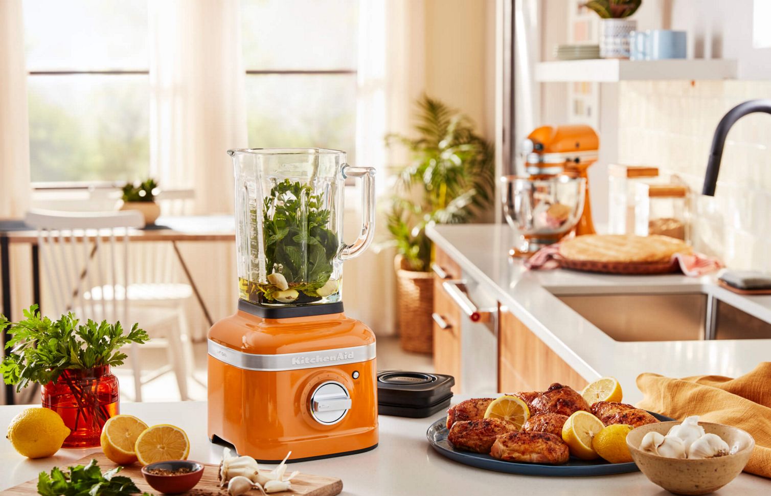 A kitchen featuring a KitchenAid® Blender in Honey filled with garlic, oil and other herbs.