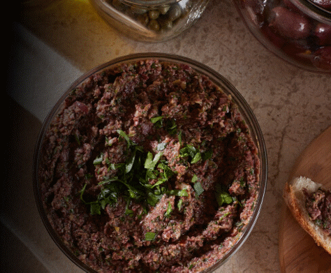An overhead close-up of a creamy bowl of olive tapenade.
