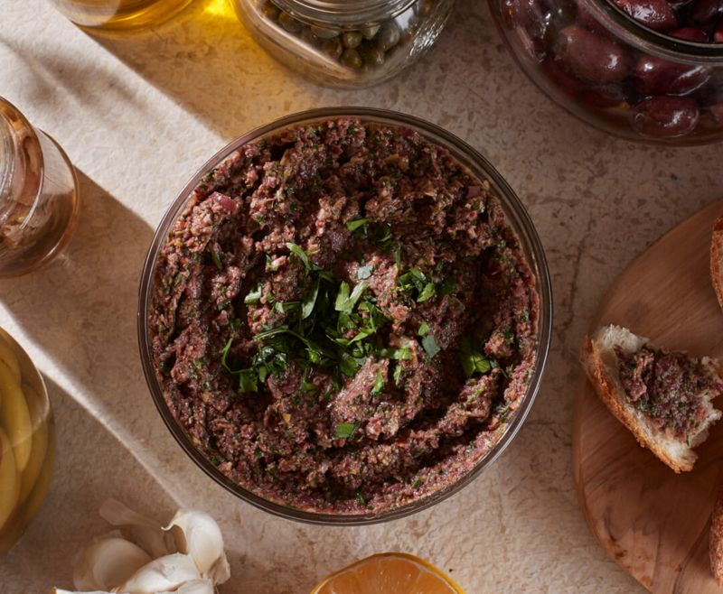 An overhead close-up of a creamy bowl of olive tapenade.