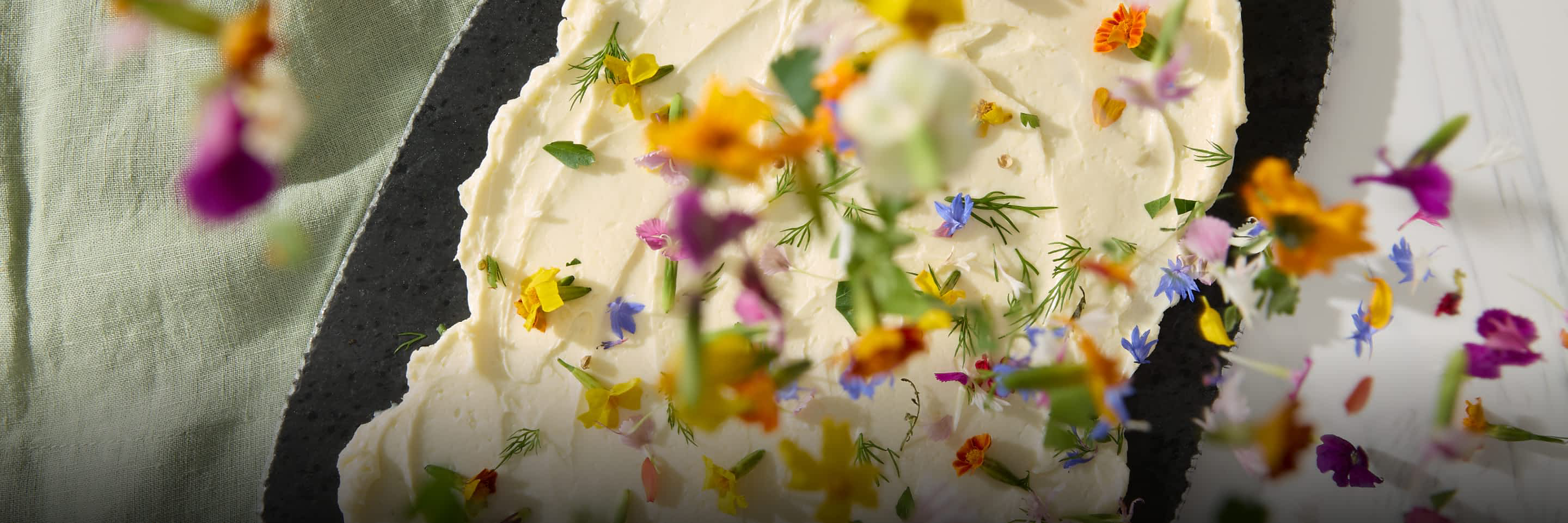 Edible flower petals being sprinkled onto butter.