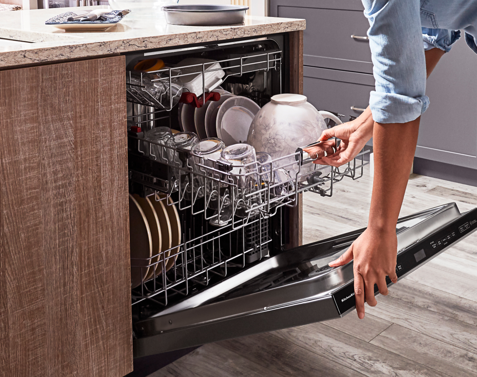 A person pulling out the fully loaded second rack of a KitchenAid® dishwasher.