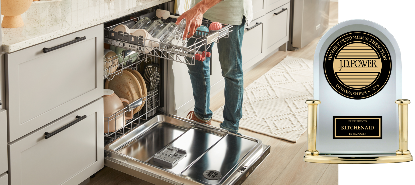A person loading items in the third rack of a dishwasher and the J.D. Power award trophy.