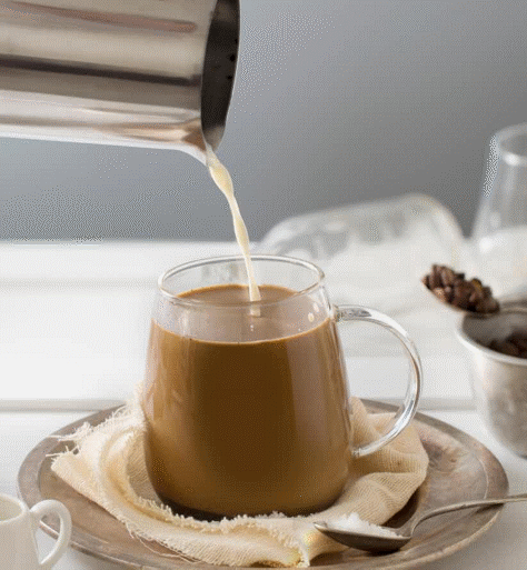Milk being poured into a cup of espresso.