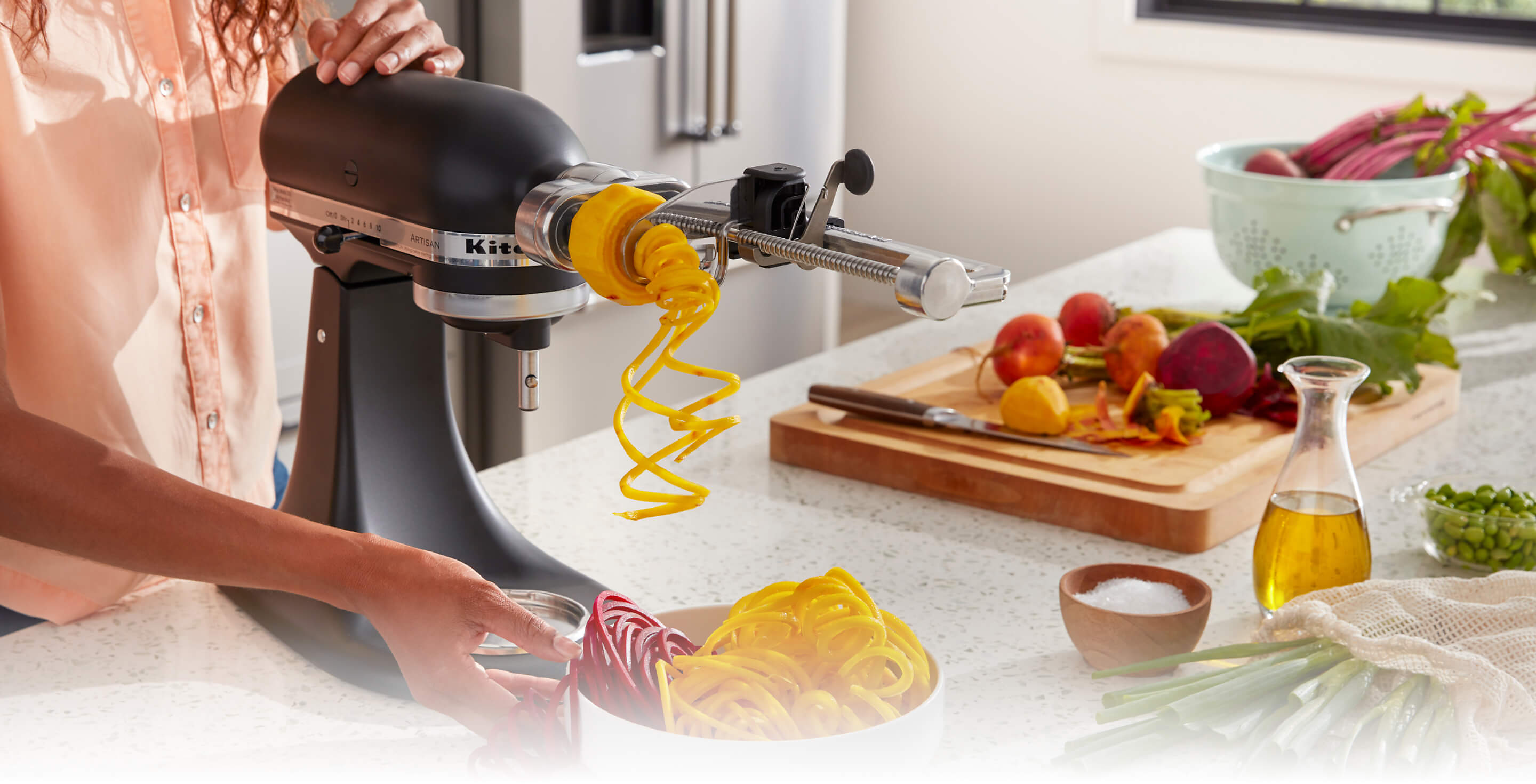 A person using the 7 Blade Spiralizer attached to a Stand Mixer.