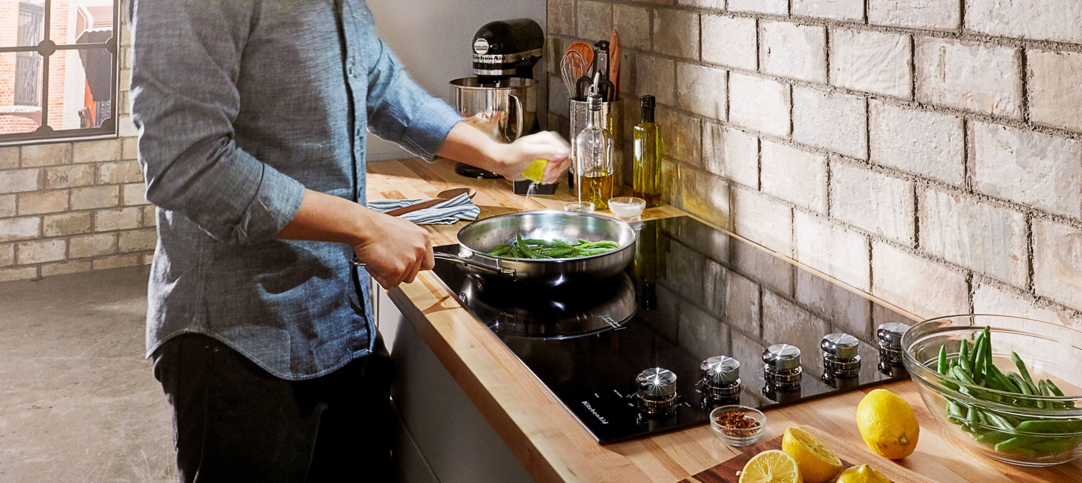 A person cooking over a KitchenAid® Cooktop.