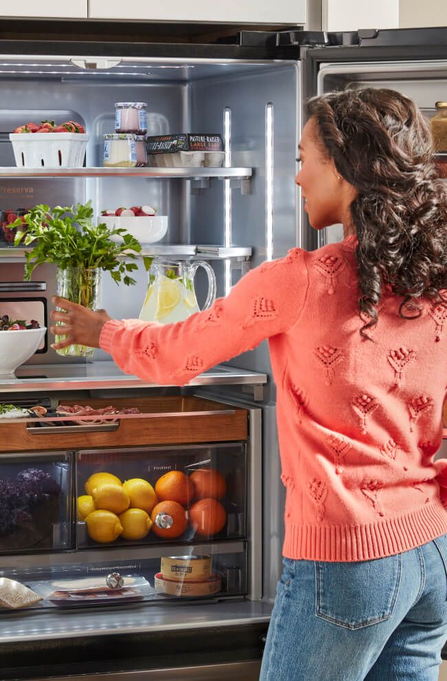 A person placing herbs in the fridge.