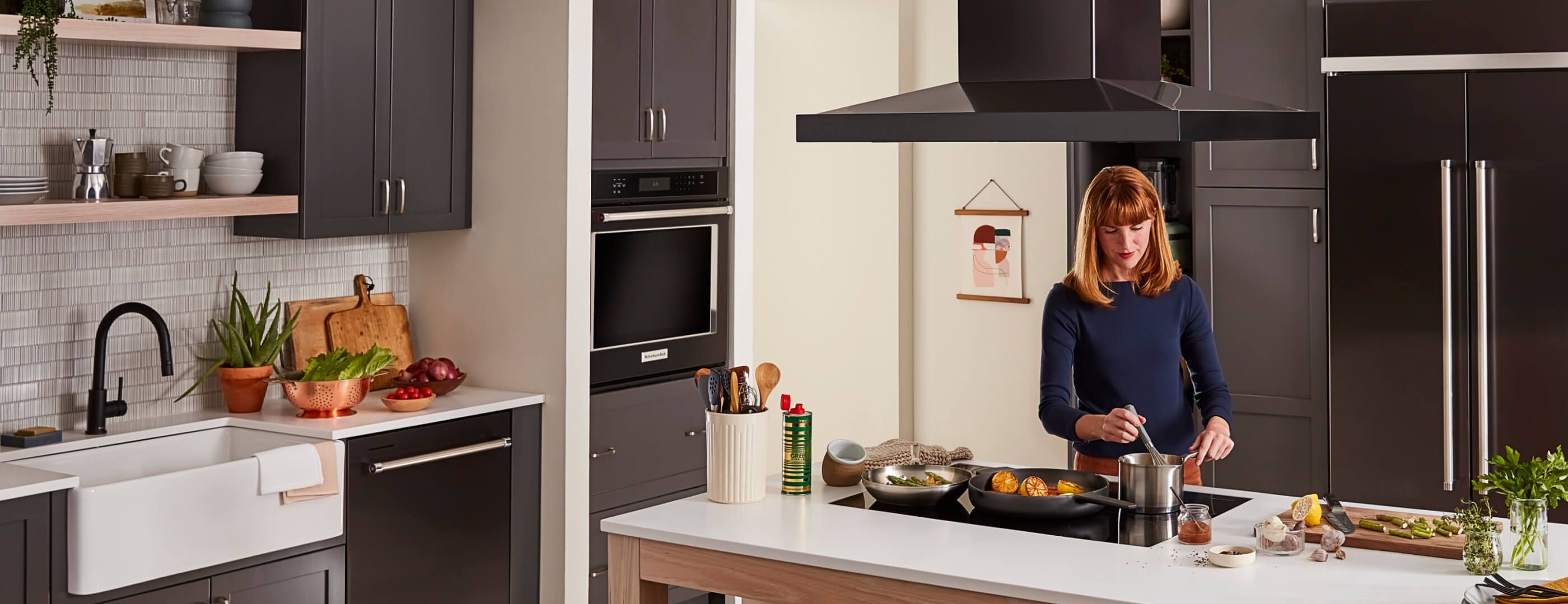 A person cooking over a cooktop in a bright, clean kitchen.
