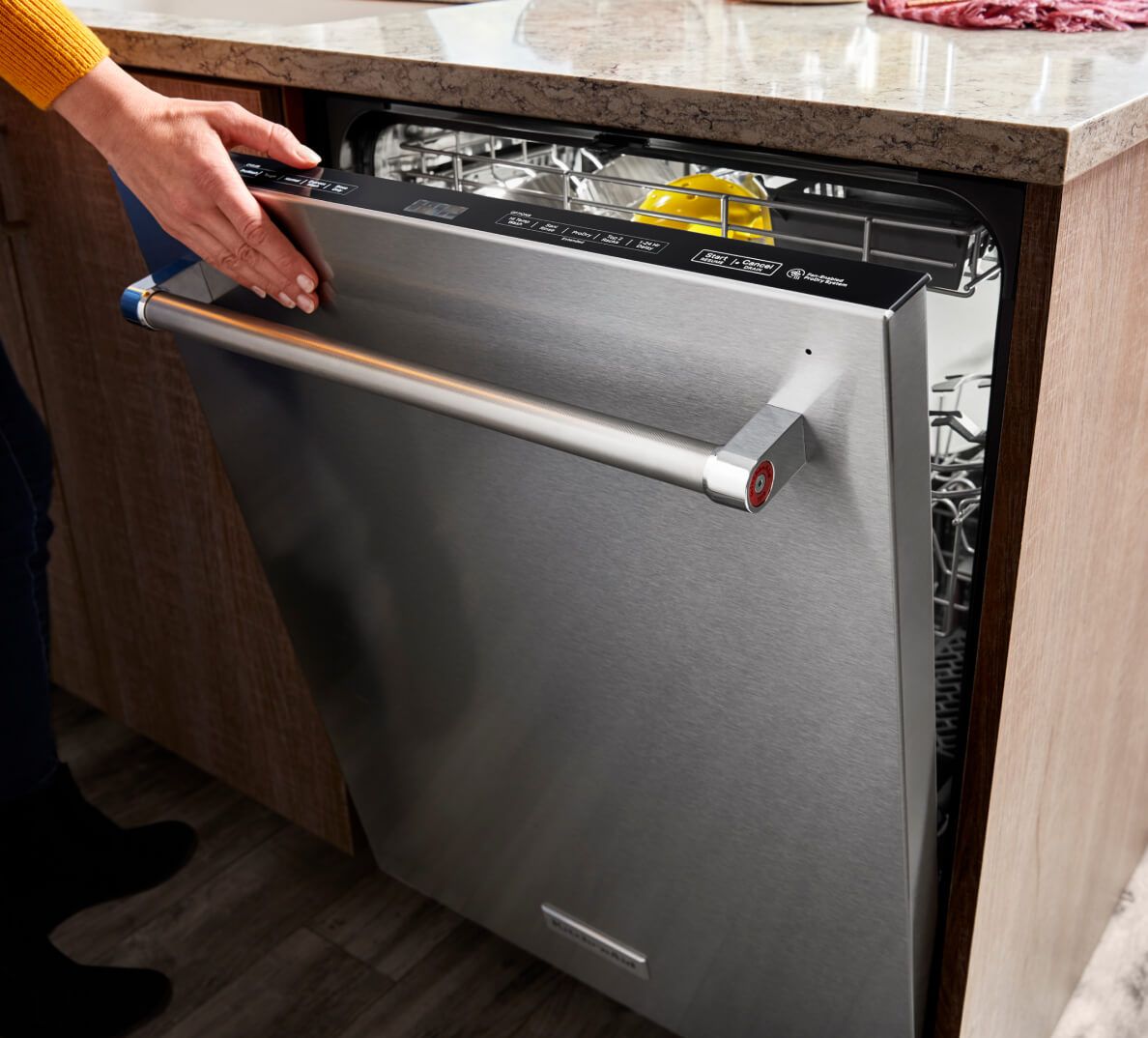 A person closing a dishwasher.