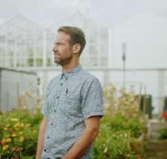 Michael M. Moore standing in his greenhouse.