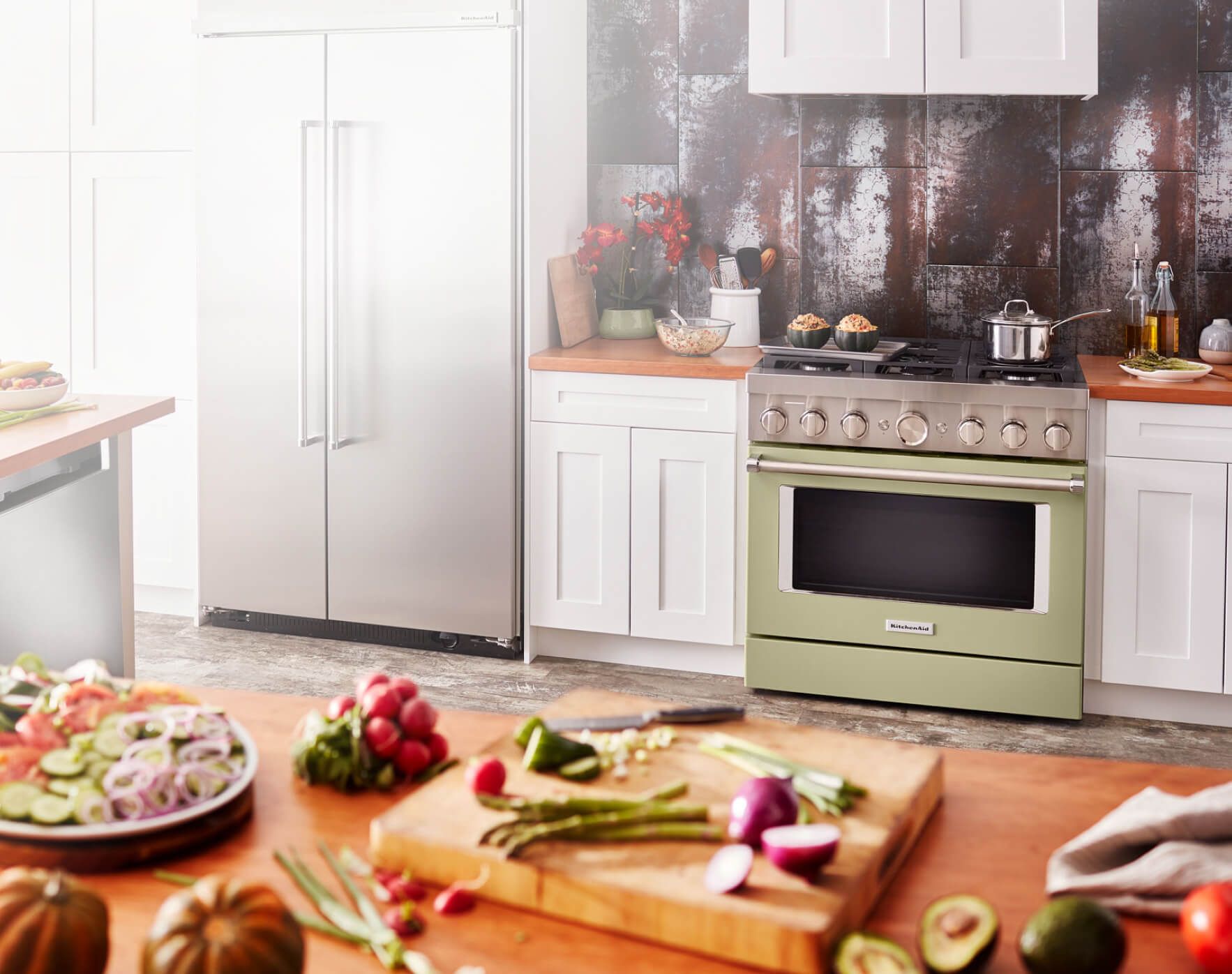 Beautiful kitchen setting with Pistachio-colored range. A table adorned with different vegetables and a cutting board.