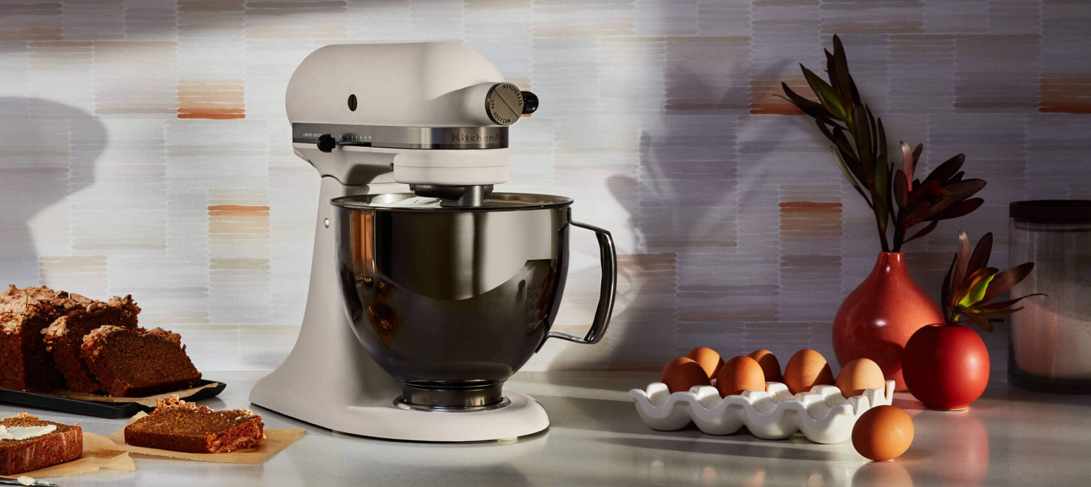 A Limited Edition Stand Mixer with a Stainless Steel Bowl surrounded by bread and eggs.