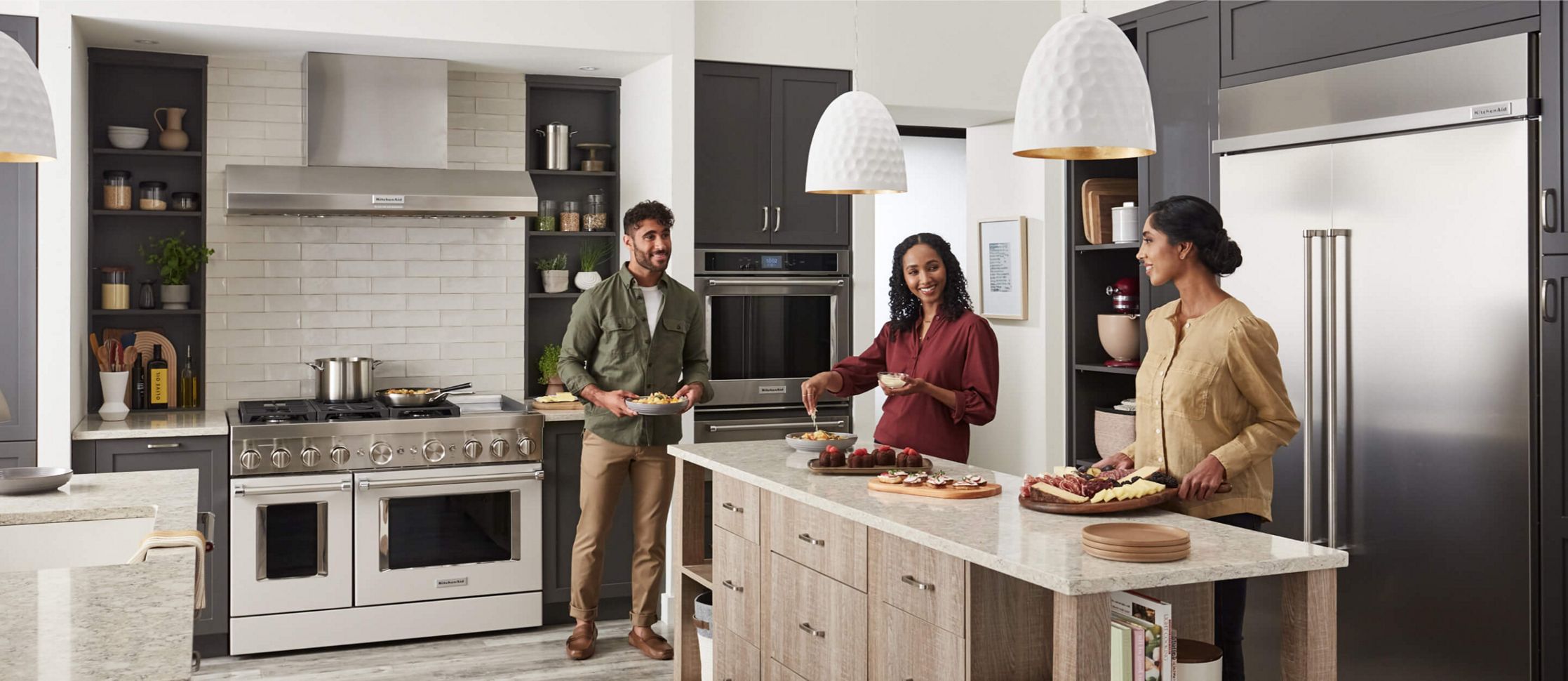 Three people gathering in a kitchen, surrounded by KitchenAid® appliances.