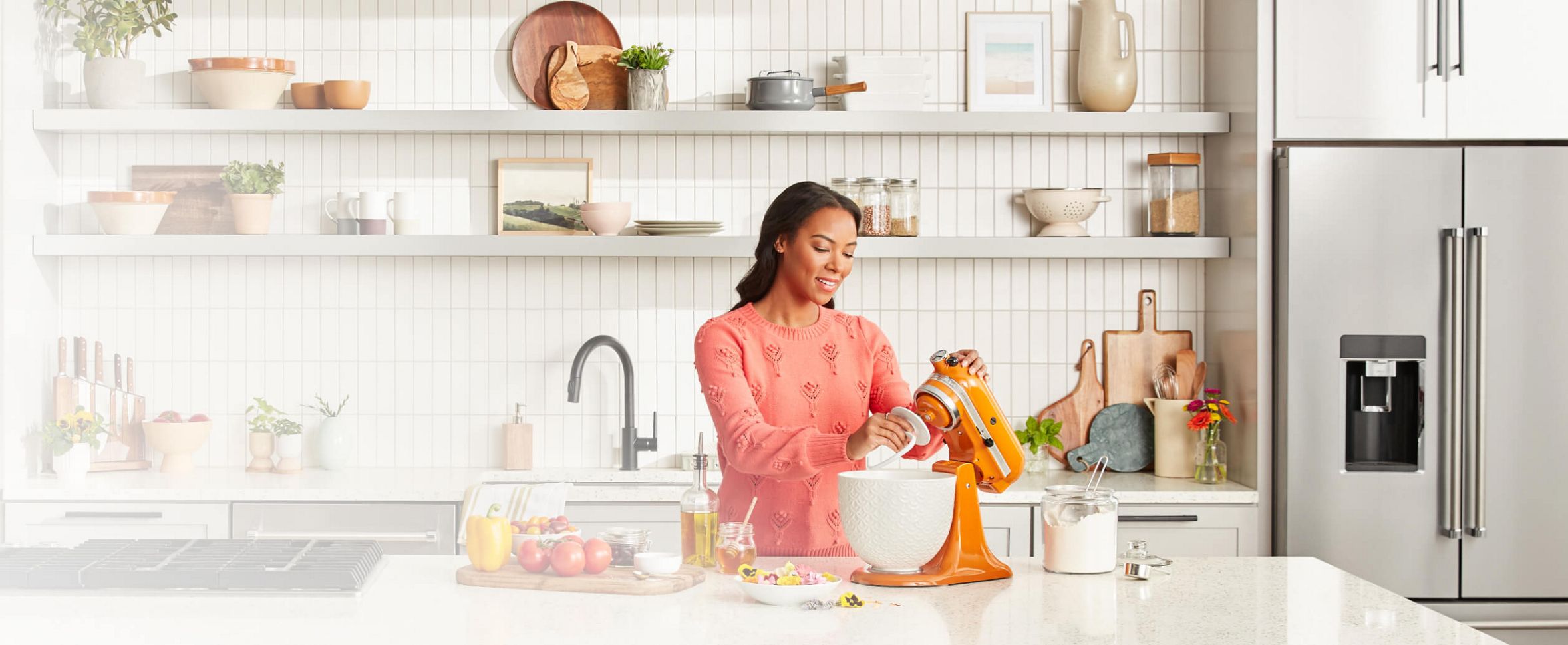 Woman in white kitchen lifting head of KitchenAid® Stand Mixer in Honey fitted with dough hook attachment.