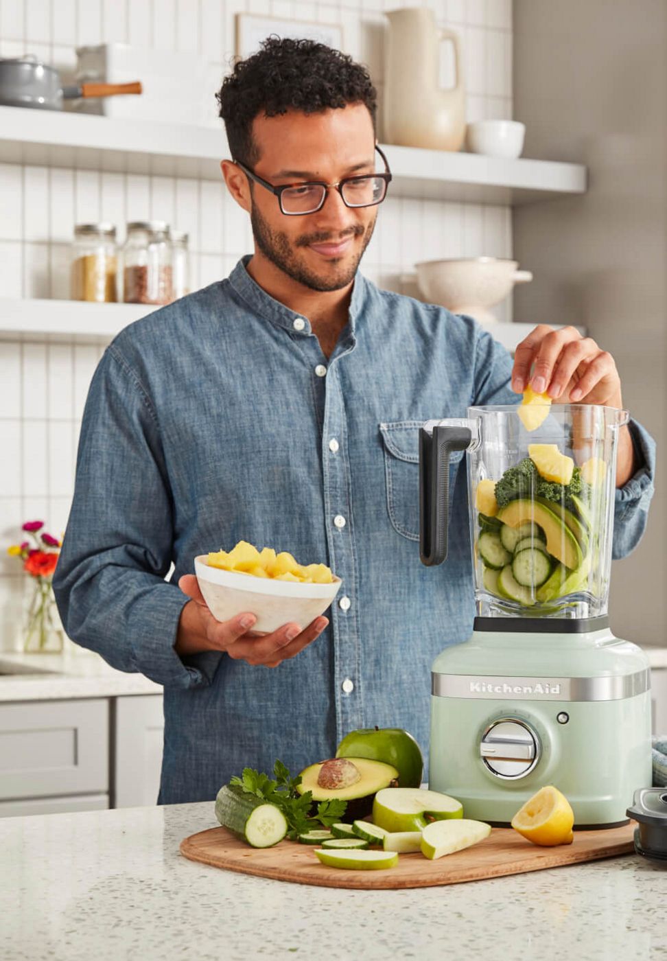 A person placing fresh produce in a KitchenAid® Blender in Pistachio.