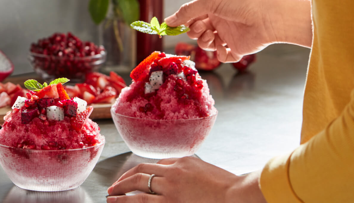 Shaved ice dessert garnished with fruit and mint.