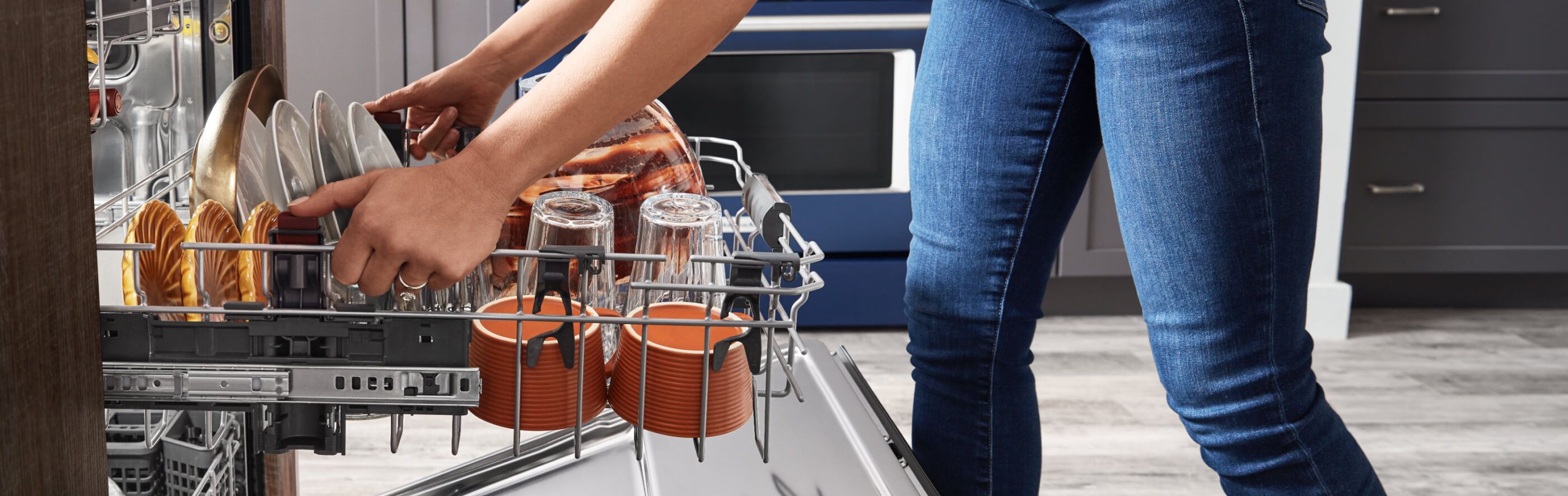 Woman adjusting upper rack in loaded dishwasher