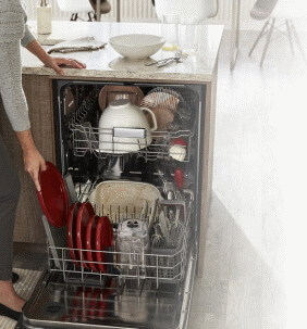 Woman loading plates into bottom rack of dishwasher