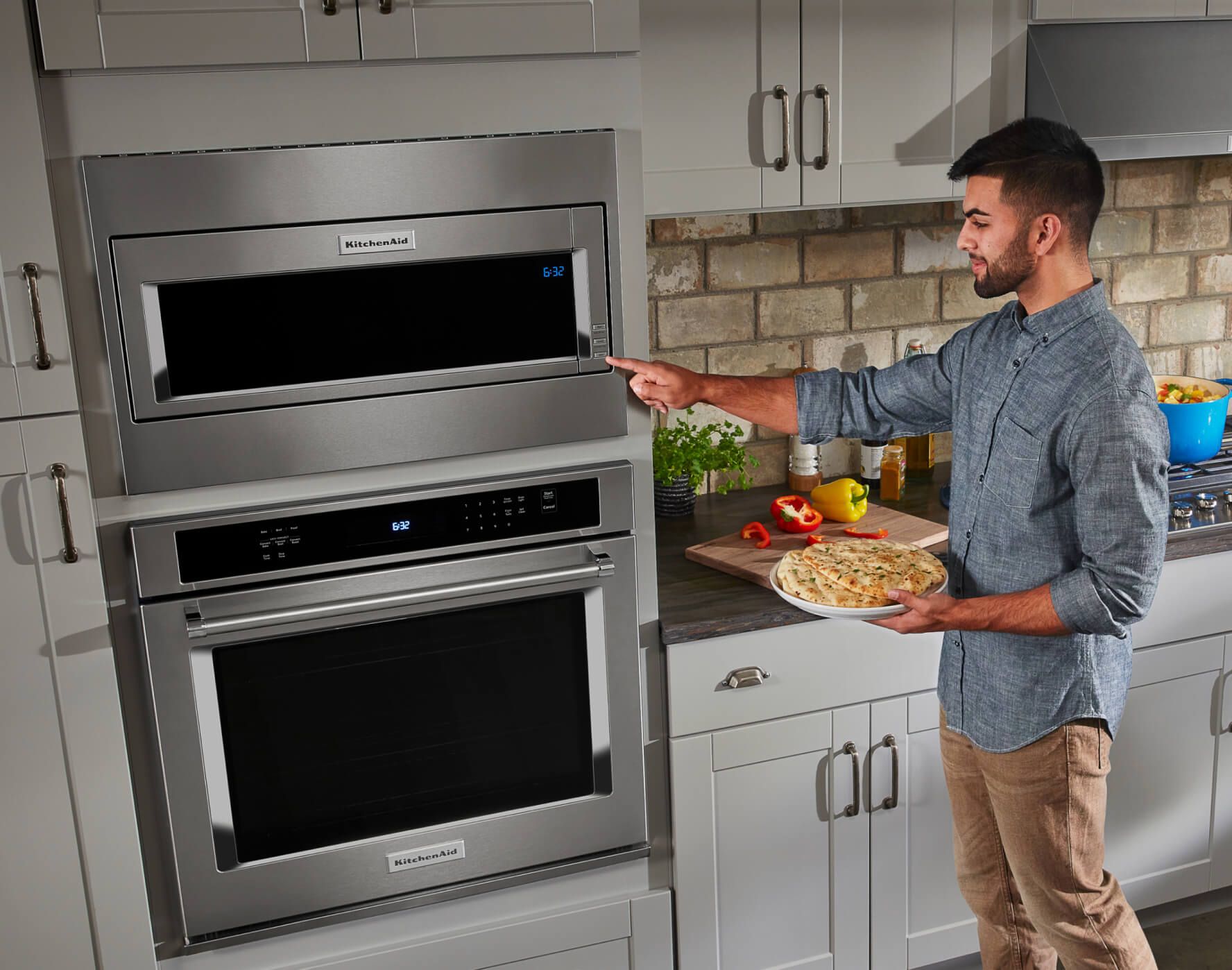 A person placing a plate of food into a KitchenAid® Microwave.