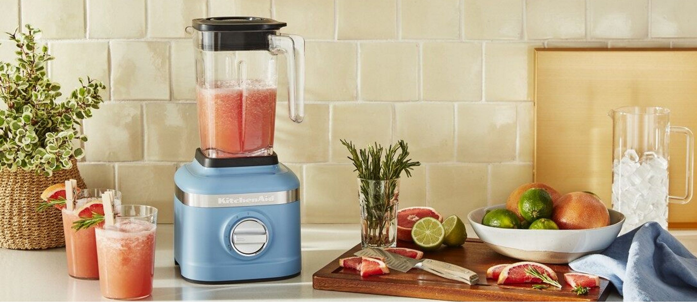 A KitchenAid® K400 Variable Speed Blender in Blue Velvet on a countertop blending fresh grapefruit drinks.