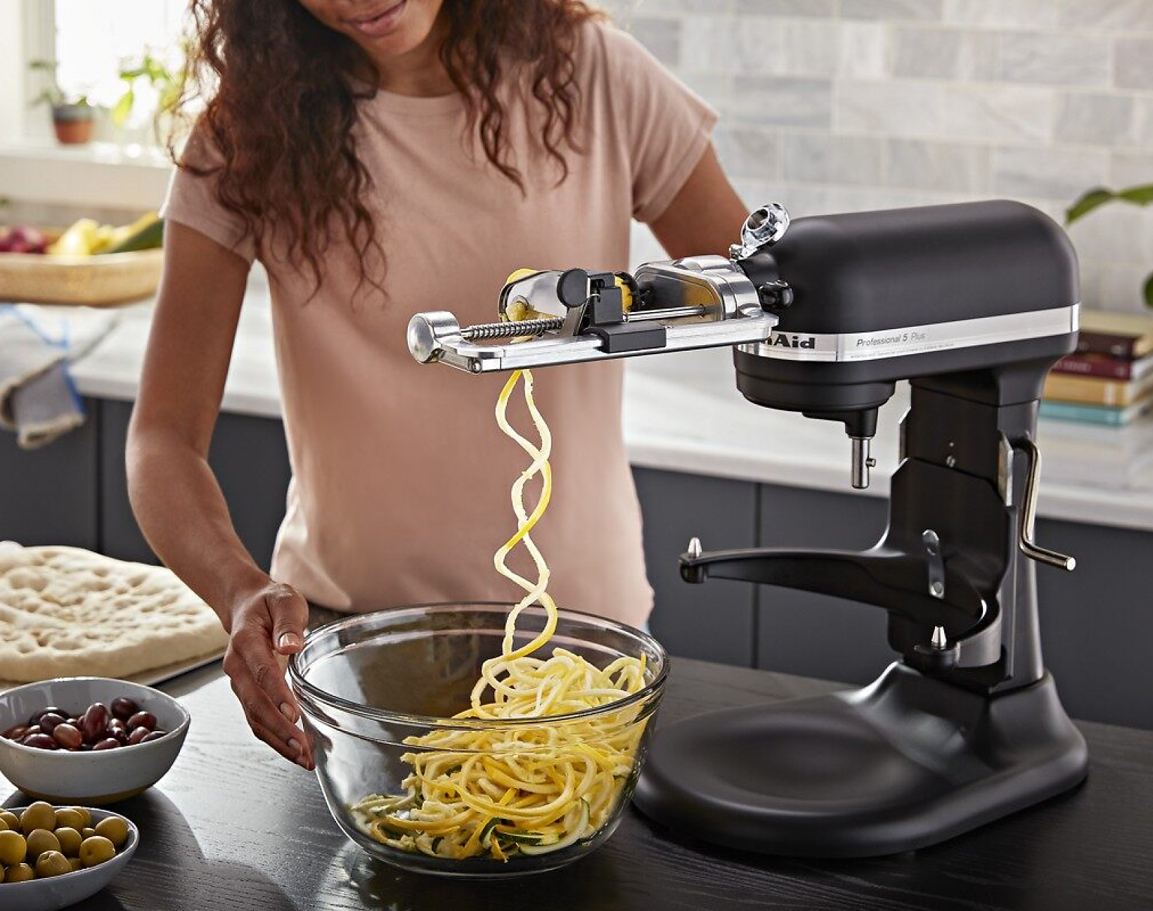 A person using the Spiralizer Attachment on a KitchenAid® Bowl-Lift Stand Mixer to make noodles out of squash.