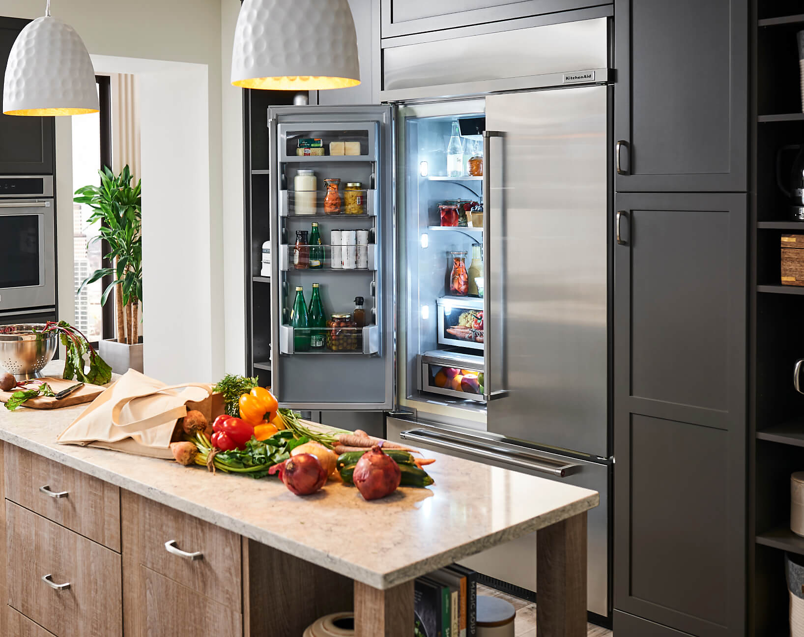 An open KitchenAid® refrigerator and produce on an island counter. 