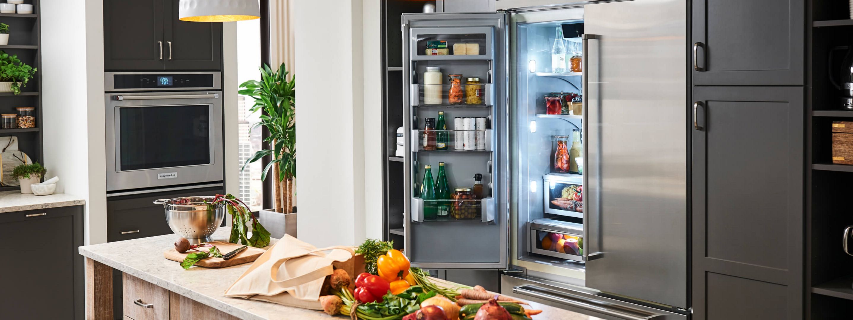 An open KitchenAid® refrigerator and produce on an island counter.