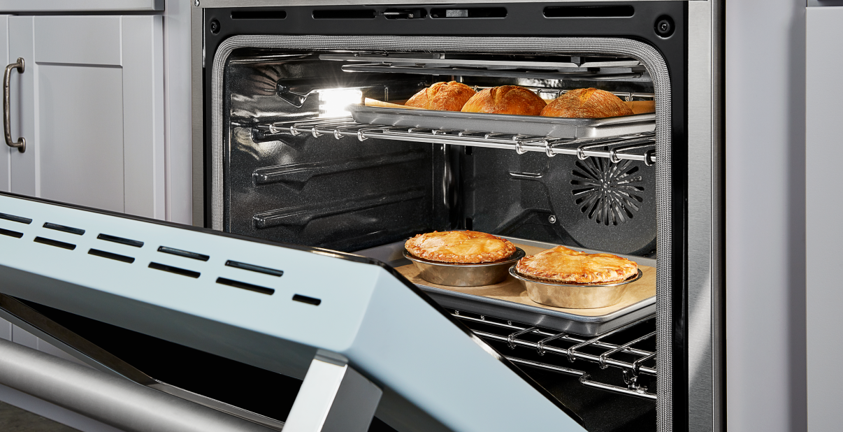 An ignited gas range with vegetables on the counter.