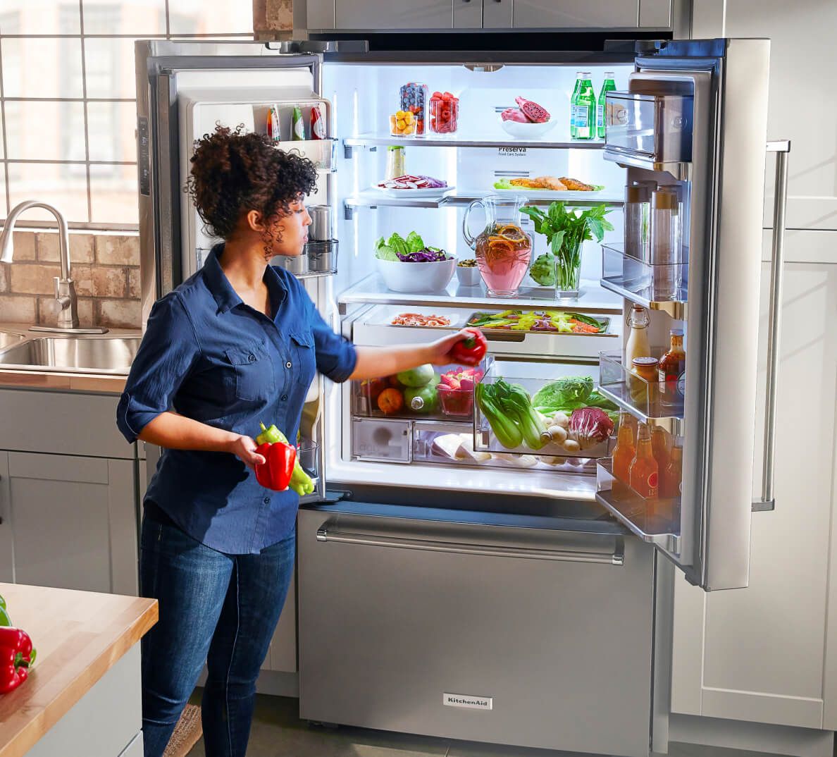 A person taking vegetables out of a refrigerators.