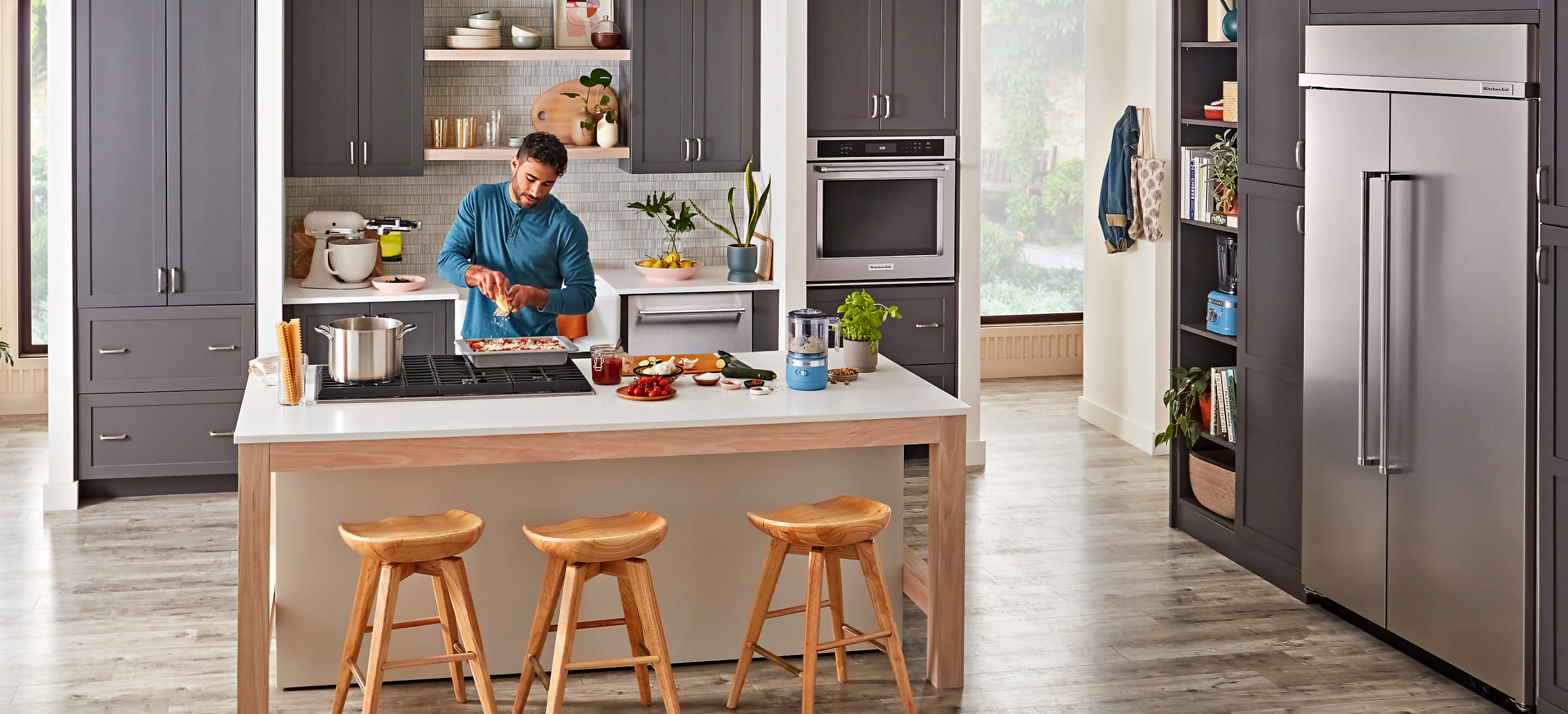 A person cooking on a cooktop in a stylish kitchen surrounded by KitchenAid® appliances. 