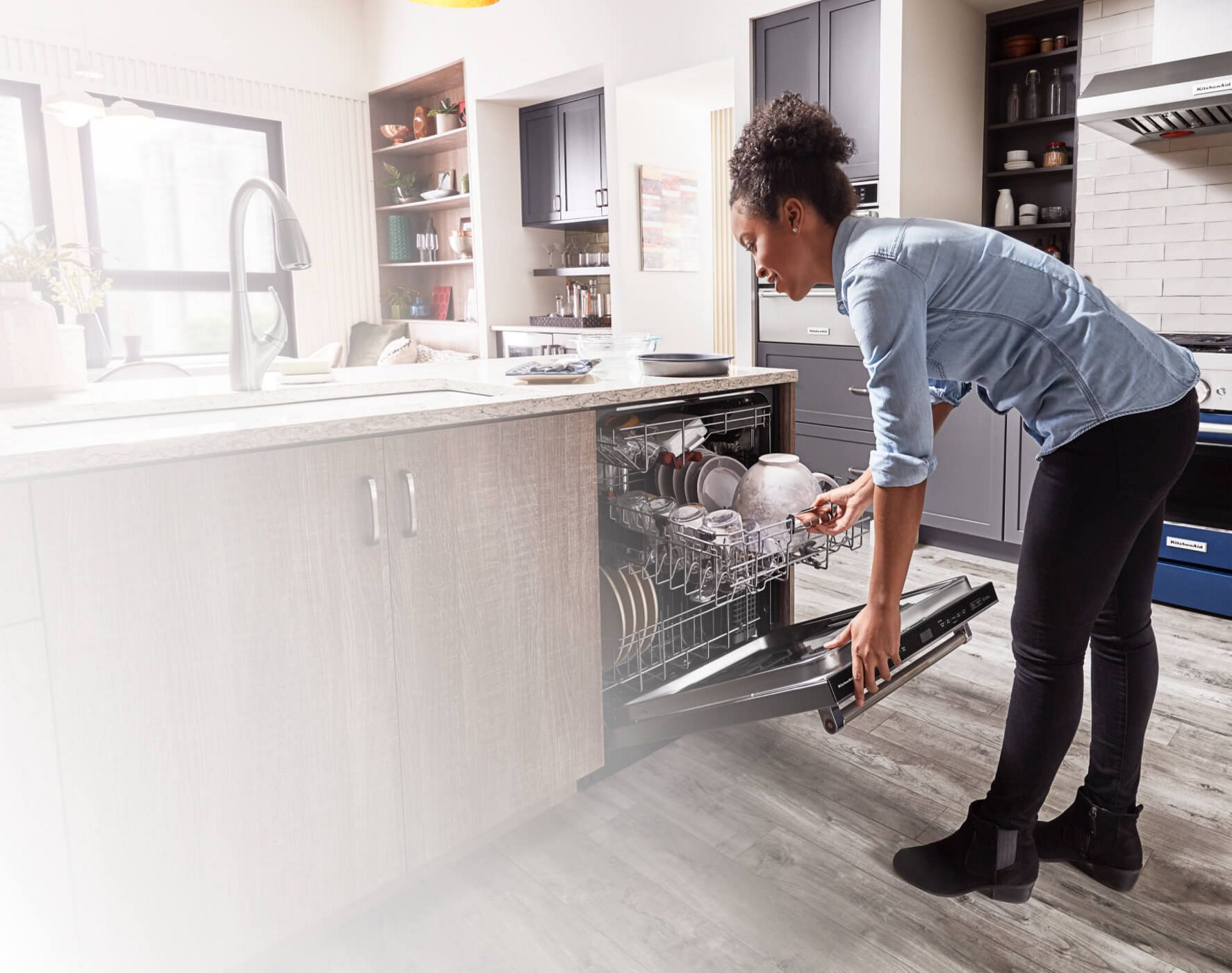 A person loading a KitchenAid® Dishwasher.