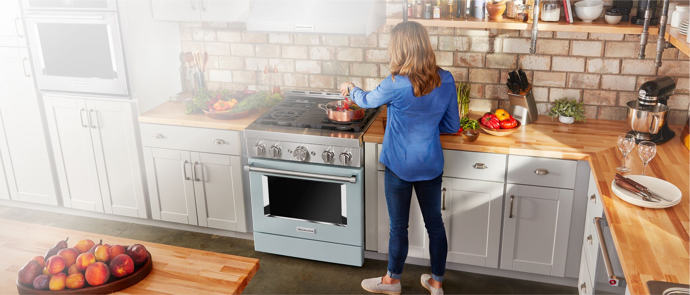 A woman cooks on a KitchenAid® commercial-style range.