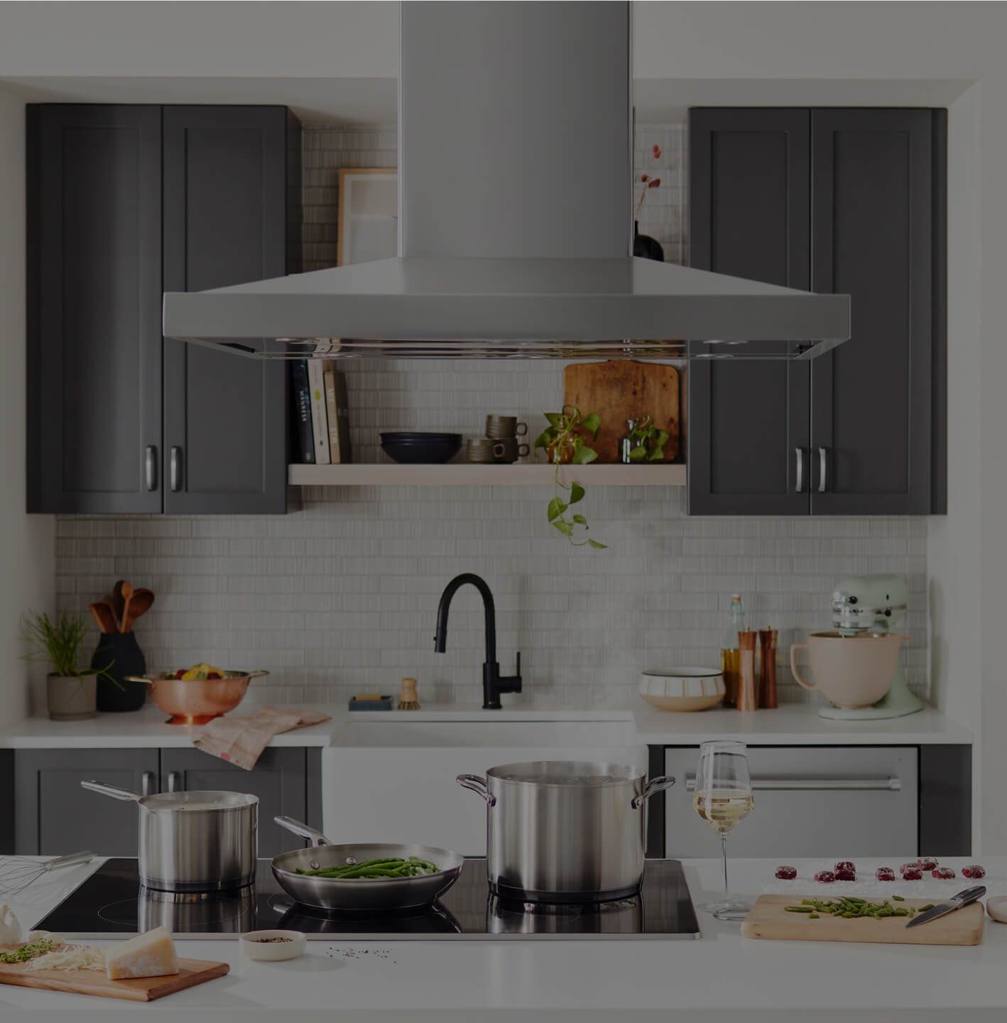 A KitchenAid® island hood above an induction cooktop.