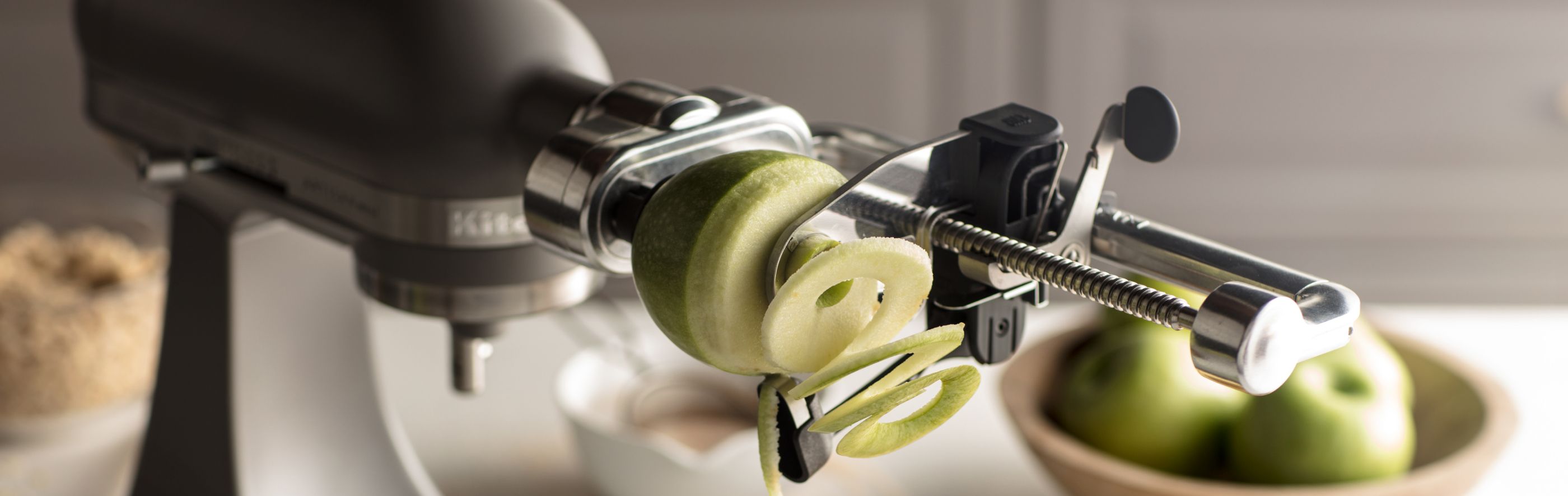 Green, Granny Smith apple being spiralized using a KitchenAid® fresh prep attachment.
