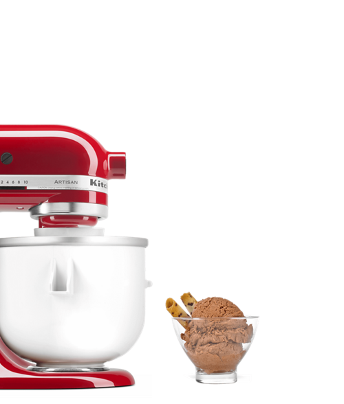 Red stand mixer equipped with ice cream maker next to bowl of chocolate ice cream and wafers.
