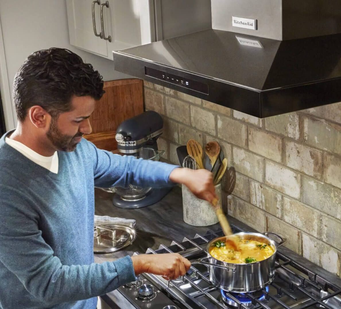Man cooking on cooktop under range hood