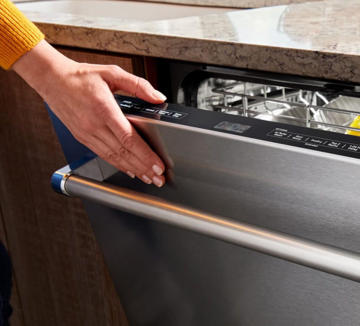 A person closing a dishwasher.
