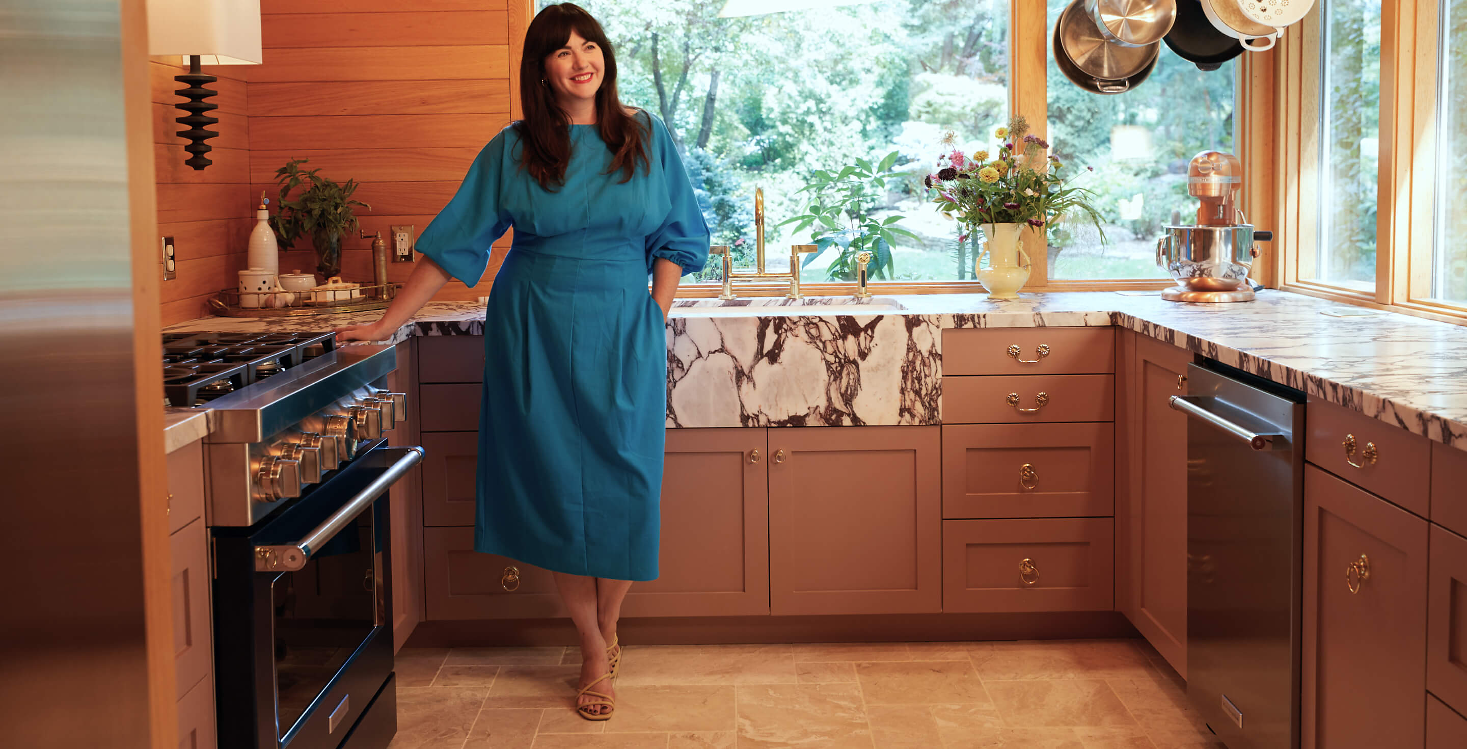 Woman standing with hands on counter behind her in kitchen with KitchenAid® appliances