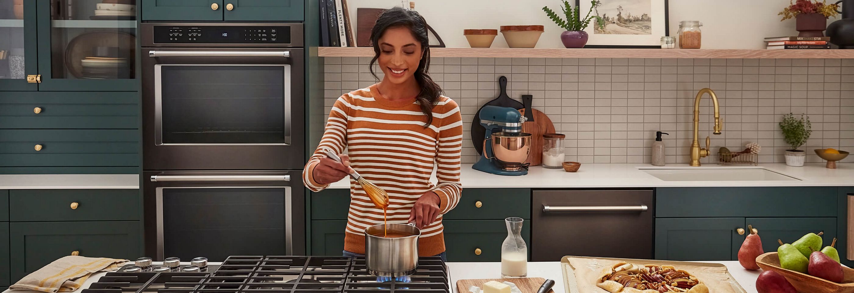 A woman whisking caramel over a KitchenAid® gas cooktop.