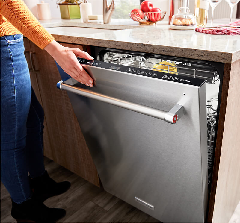 A person opening a KitchenAid® dishwasher. 