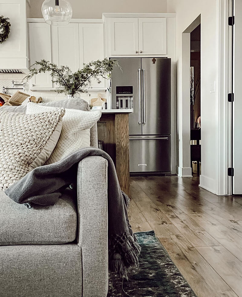 A white kitchen with a couch in the foreground. Features a KitchenAid® French door refrigerator.