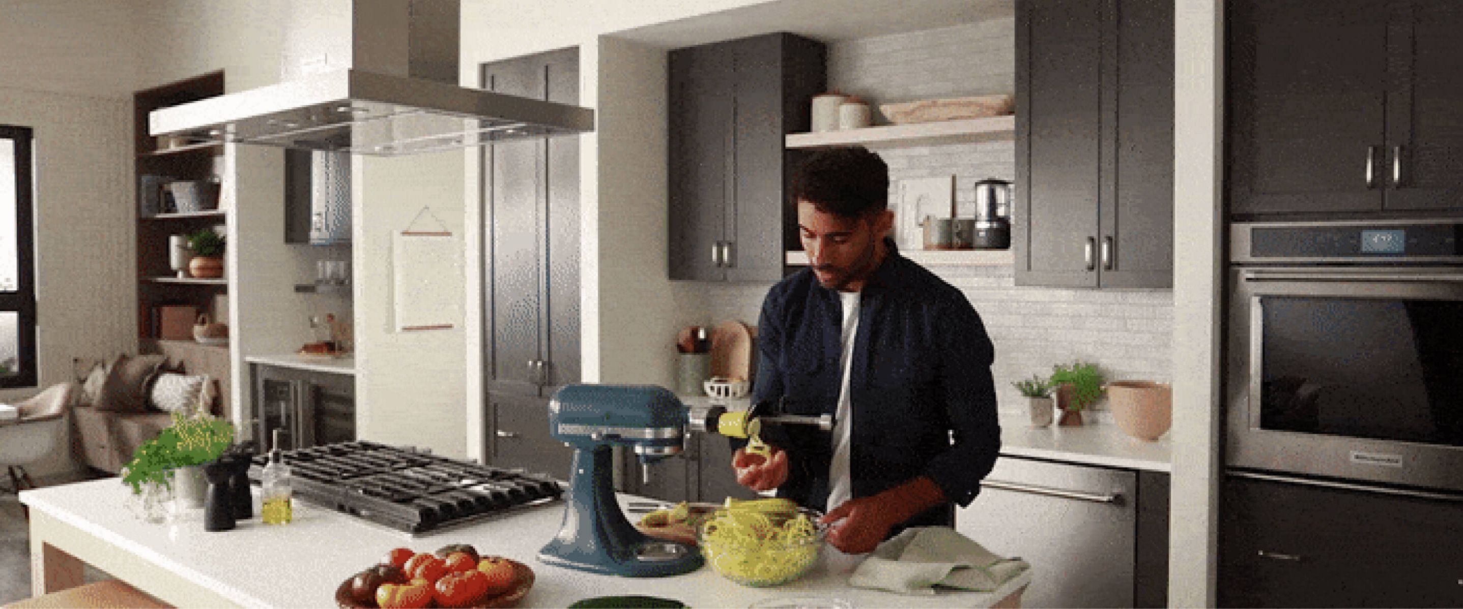 A person spiralizing zucchini with a KitchenAid® stand mixer.