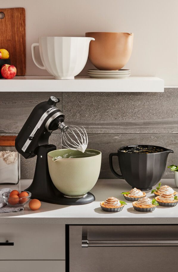 A black KitchenAid® stand mixer surrounded by mini tarts.