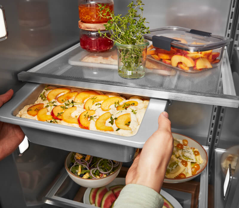 KitchenAid® Built-In Side-by-Side Refrigerator Under-Shelf Prep Zone holding a peach dessert  