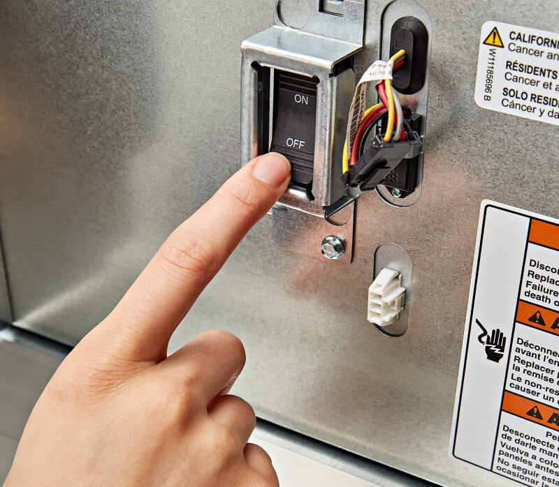 A person pressing the ON/OFF Power Switch on the KitchenAid® Built-In Side-by-Side Refrigerator