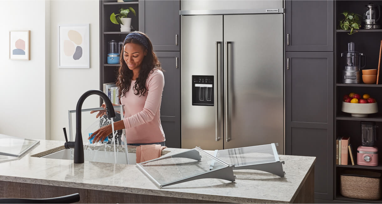 A maker washing the interior bins and shelves of a KitchenAid® Built-In Side-by-Side Refrigerator